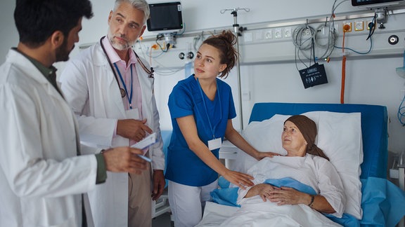 Ärzte und Pfleger stehen an einem Patientenbett.