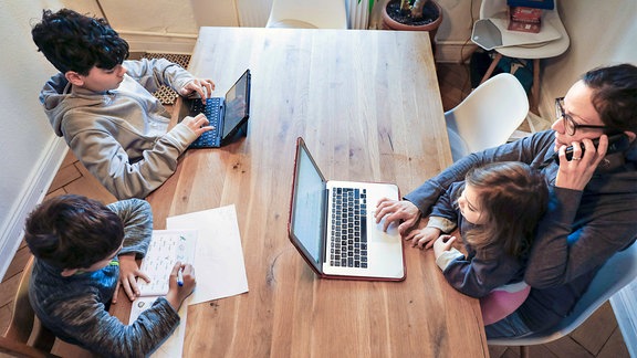 Berufstätige Mutter mit Kindern im Homeoffice. 