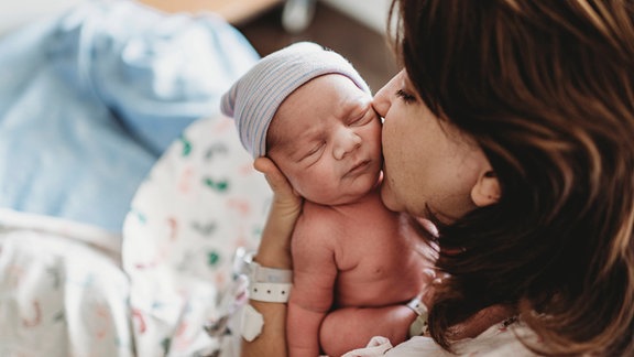 Mutter küsst neugeborenes Baby.