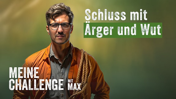 Ein junger Mann mit schwarzer Brille, Drei-Tage-Bart, kurzen dunklen Haaren, grauem Hemd und einer geöffneten, orangenfarbenen Outdoorjacke hat ein Seil auf seiner linken Schulter liegen.