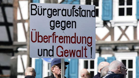 Ein Demonstrant trägt ein Schild mit der Aufschrift Aufstand der Bürger gegen ausländische Unterwanderung und Gewalt. 