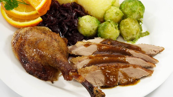 Gänsebraten mit Klößen, Rotkraut und Rosenkohl auf einem Teller