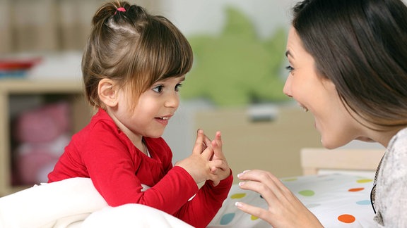 Symbolfoto - Mutter und kleine Tochter spielen gestikulierend miteinander.