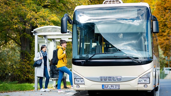 Zwei Menschen steigen an einer Haltestelle im Kreis Saalfeld-Rudolstadt in einen Linienbus.