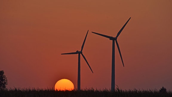 Zwei Windräder vor einem Sonnenuntergang