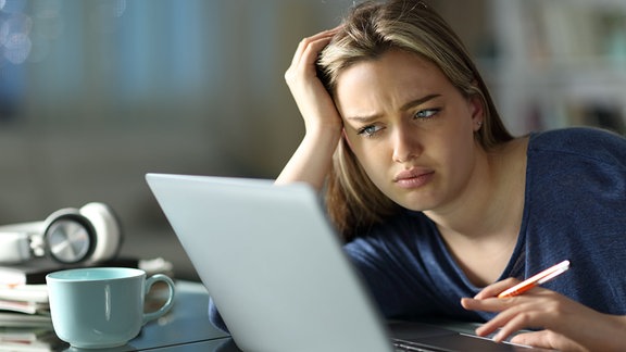 Symbolbild: Frau grübelt an einem Laptop.