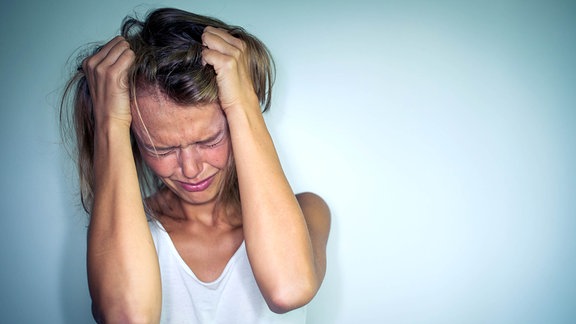 Eine junge Frau mit Händen in den Haaren.